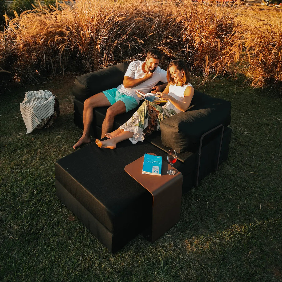 Varanda com puffs modulares, almofadas e lareira de mesa acesa no fim da tarde