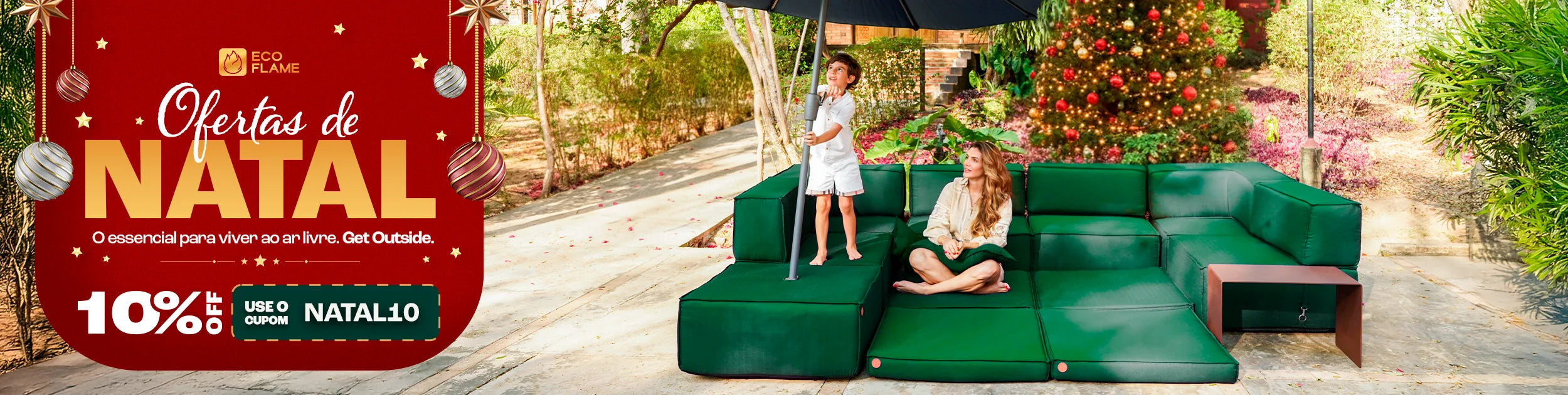 Casal sentado em um sofá cinza em uma sala de estar aconchegante. Eles estão sorrindo e segurando canecas laranja. No fundo, uma estante com livros e objetos decorativos. No topo da imagem, o texto 'Mês dos NAMORADOS' com um coração laranja, e à direita, um banner laranja com o texto 'Site até 35% OFF +30 DIAS PARA TESTAR'. O casal está usando meias coloridas e parecem estar relaxados e felizes.